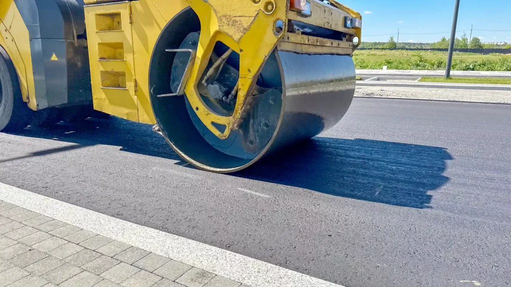 A roller compacting and levelling a resurfaced road